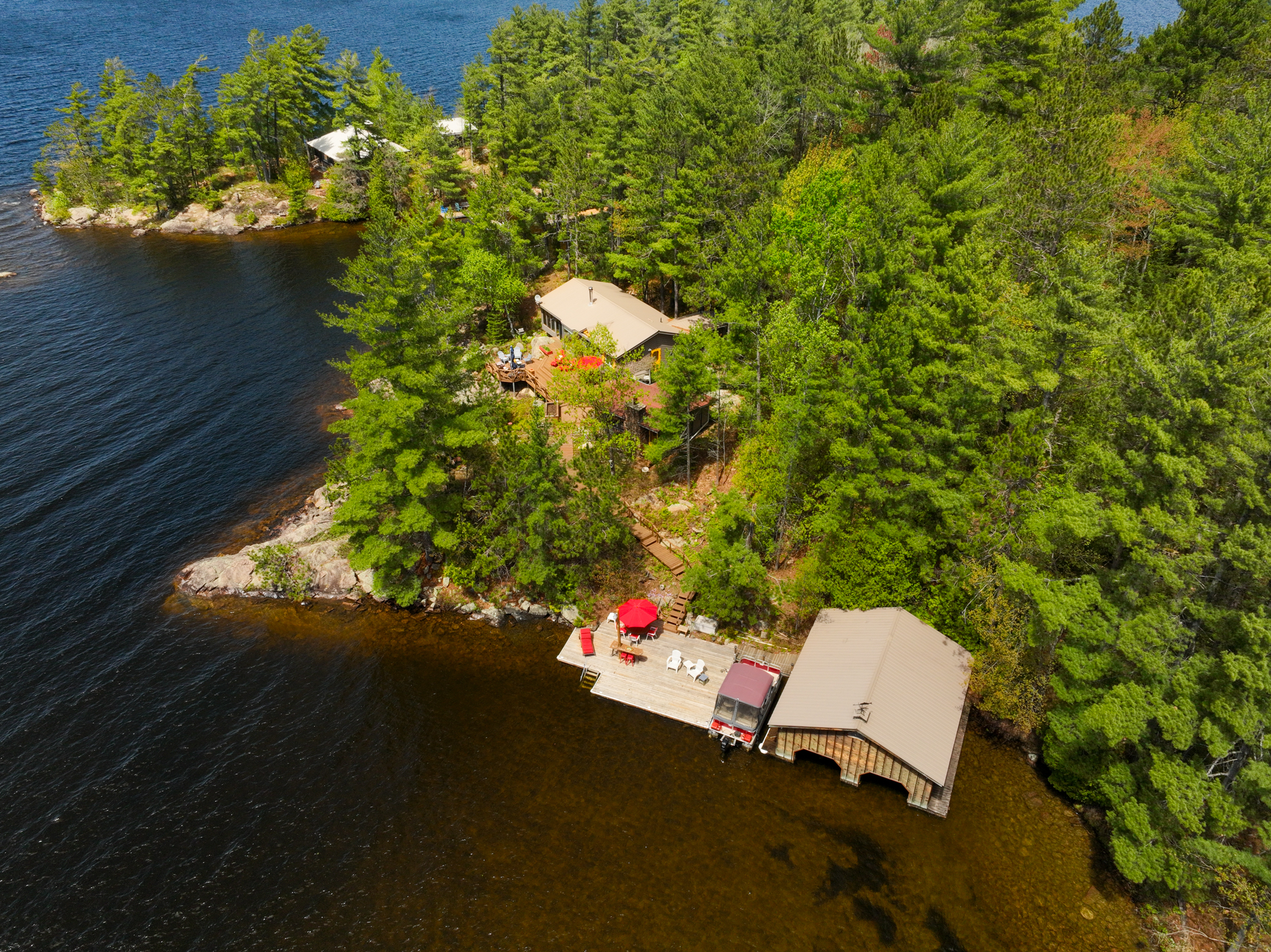 Drone image showing cottage buildings, dock, and wooded shoreline curving around the bay