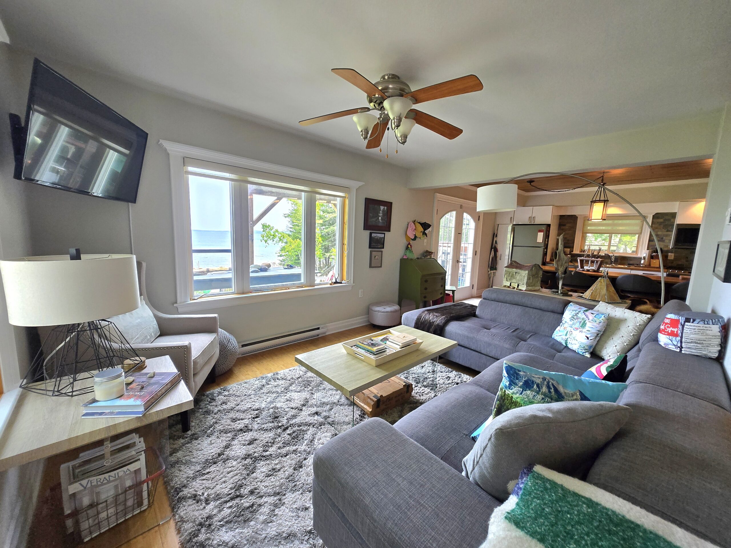 Large living area with ceiling fan, sectional couch, and TV
