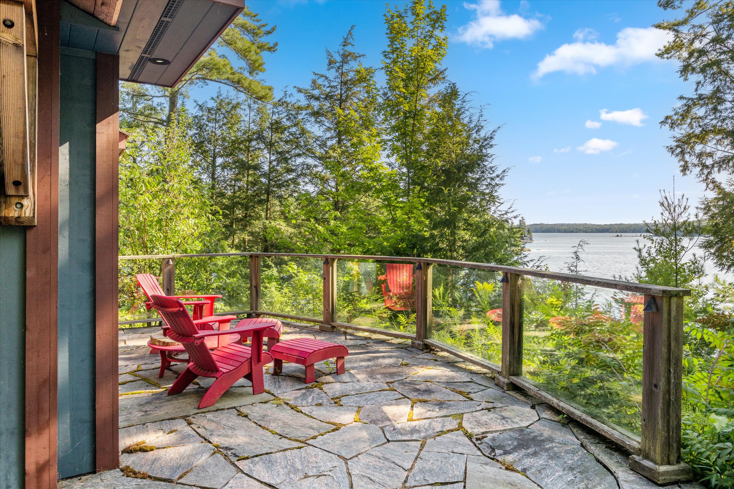 Stone patio with Muskoka chairs overlooking the lake from the guest cottage