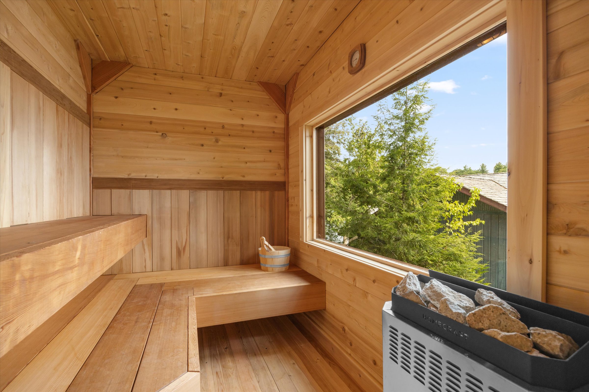 Modern wooden sauna room with large picture window offering serene lake views