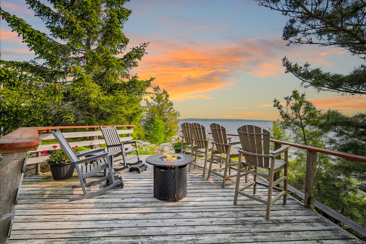 Upper deck with patio furniture and fire table set under glowing sunset sky