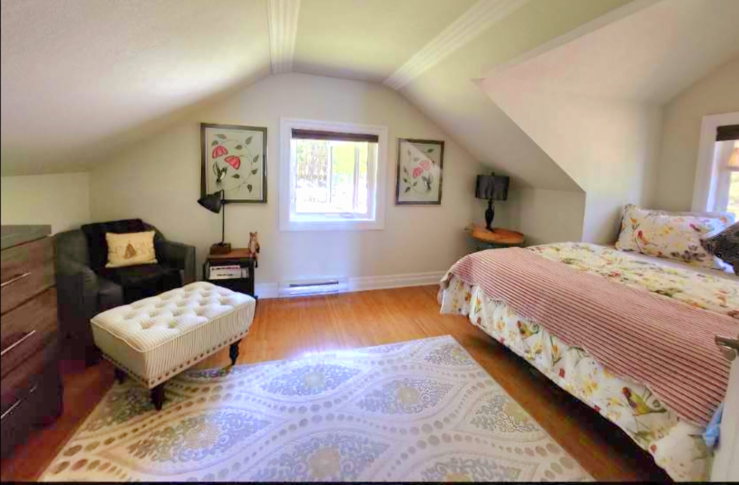 Comfortable bedroom with double bed, armchair, and angled ceiling