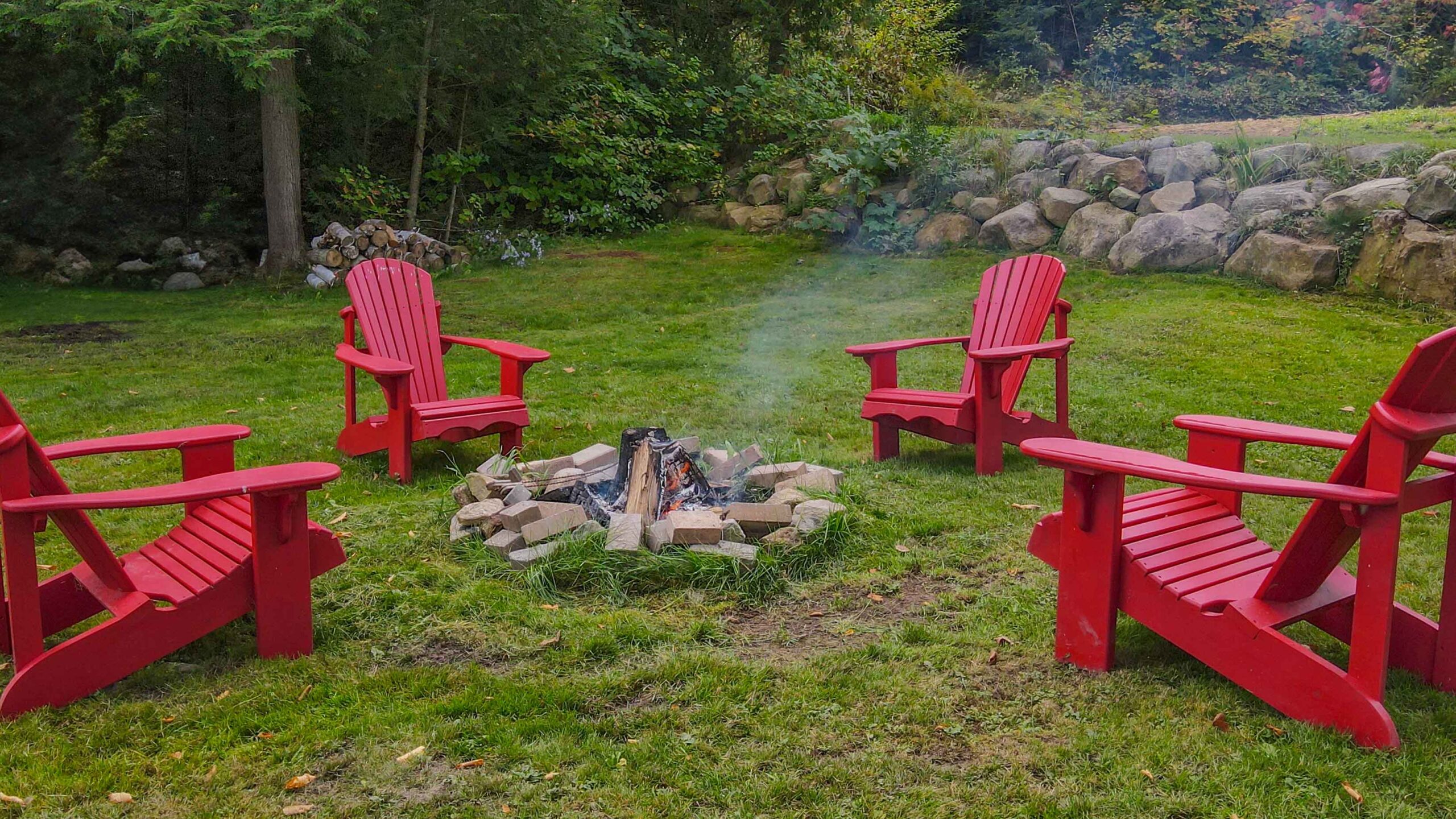 A firepit surrounded by red Muskoka chairs, ideal for cozy evening gatherings.