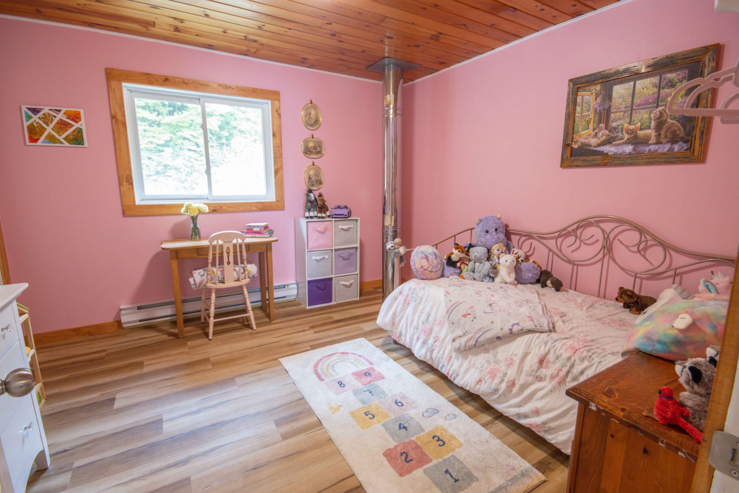 Cosy pink bedroom with a single bed, rug, and a study area.