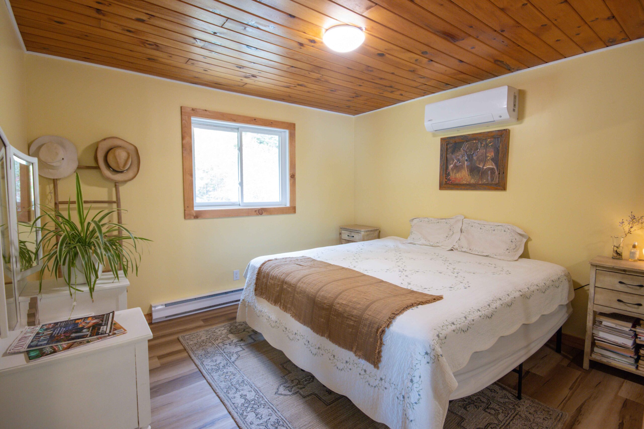 Airy main bedroom with hardwood floors and wall-mounted A/C.