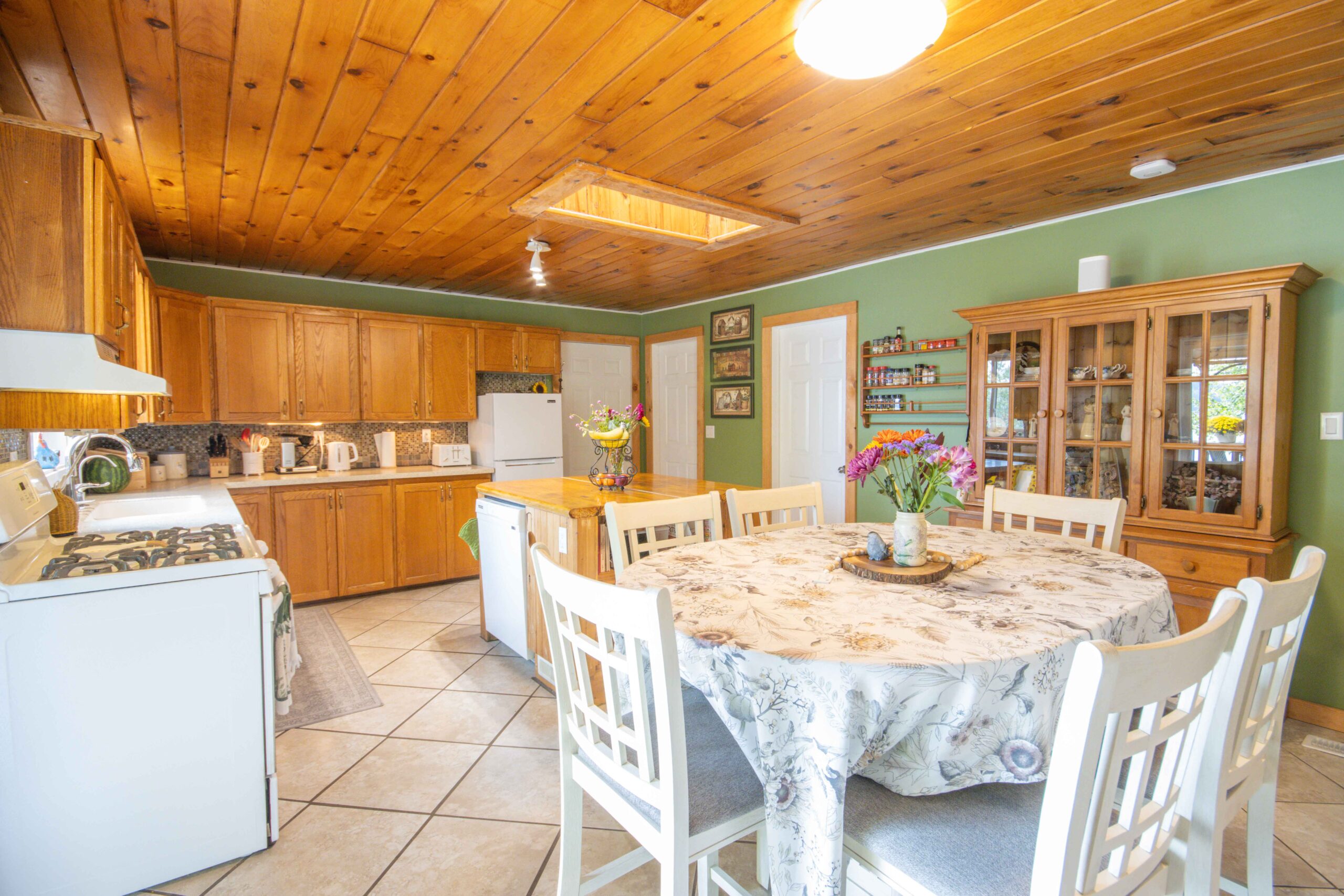 Bright dining room with round table, white chairs, and tile floors.