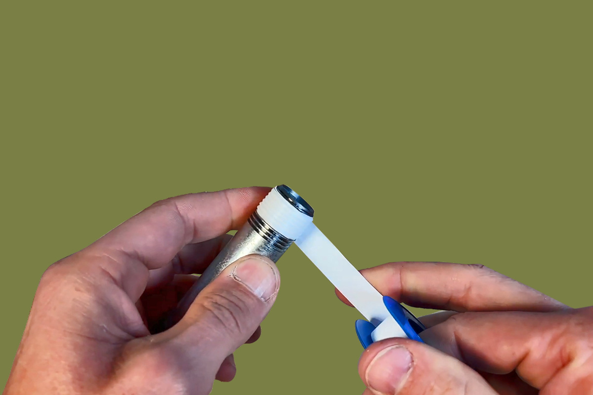 A set of hands wrapping tape around a pipe end