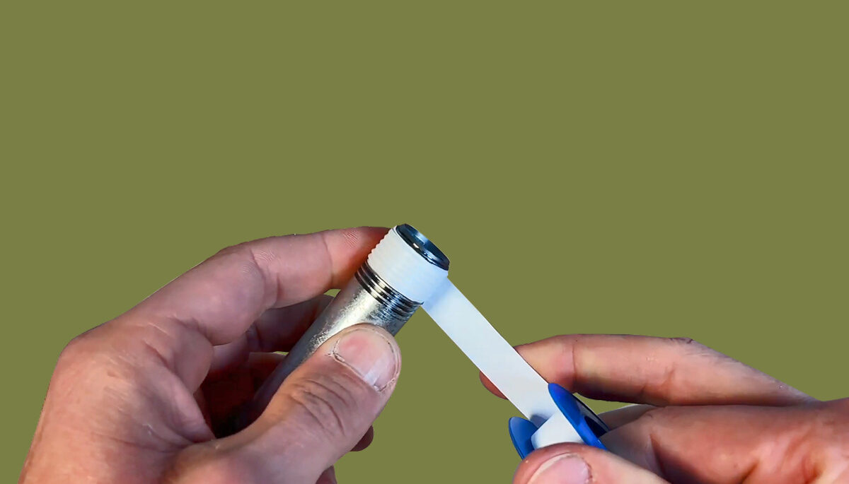 A set of hands wrapping tape around a pipe end