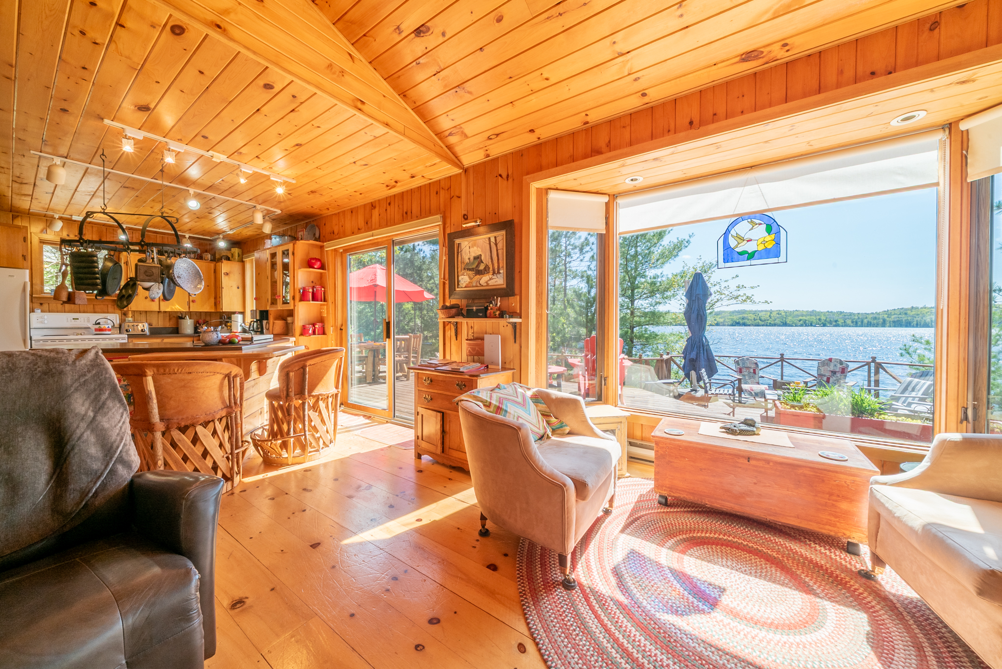 Spacious sitting area with leather seating, wood ceilings, and sweeping views of Mazinaw Lake