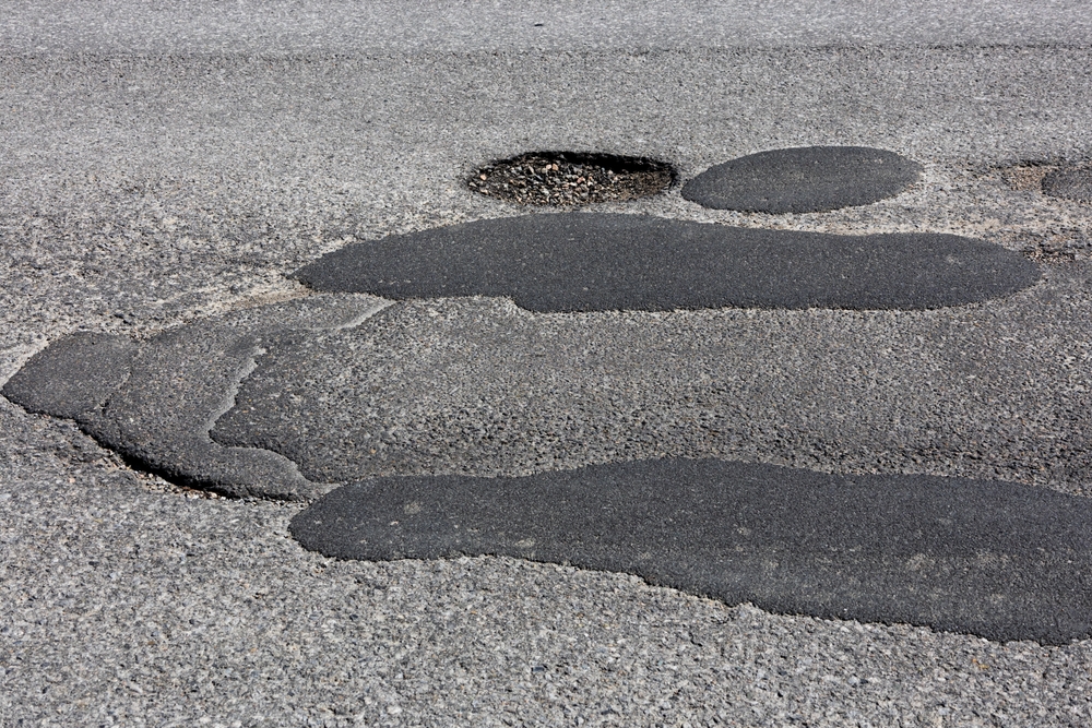 Horizontal view of badly patched asphalt pavement and pothole on a road in Canada