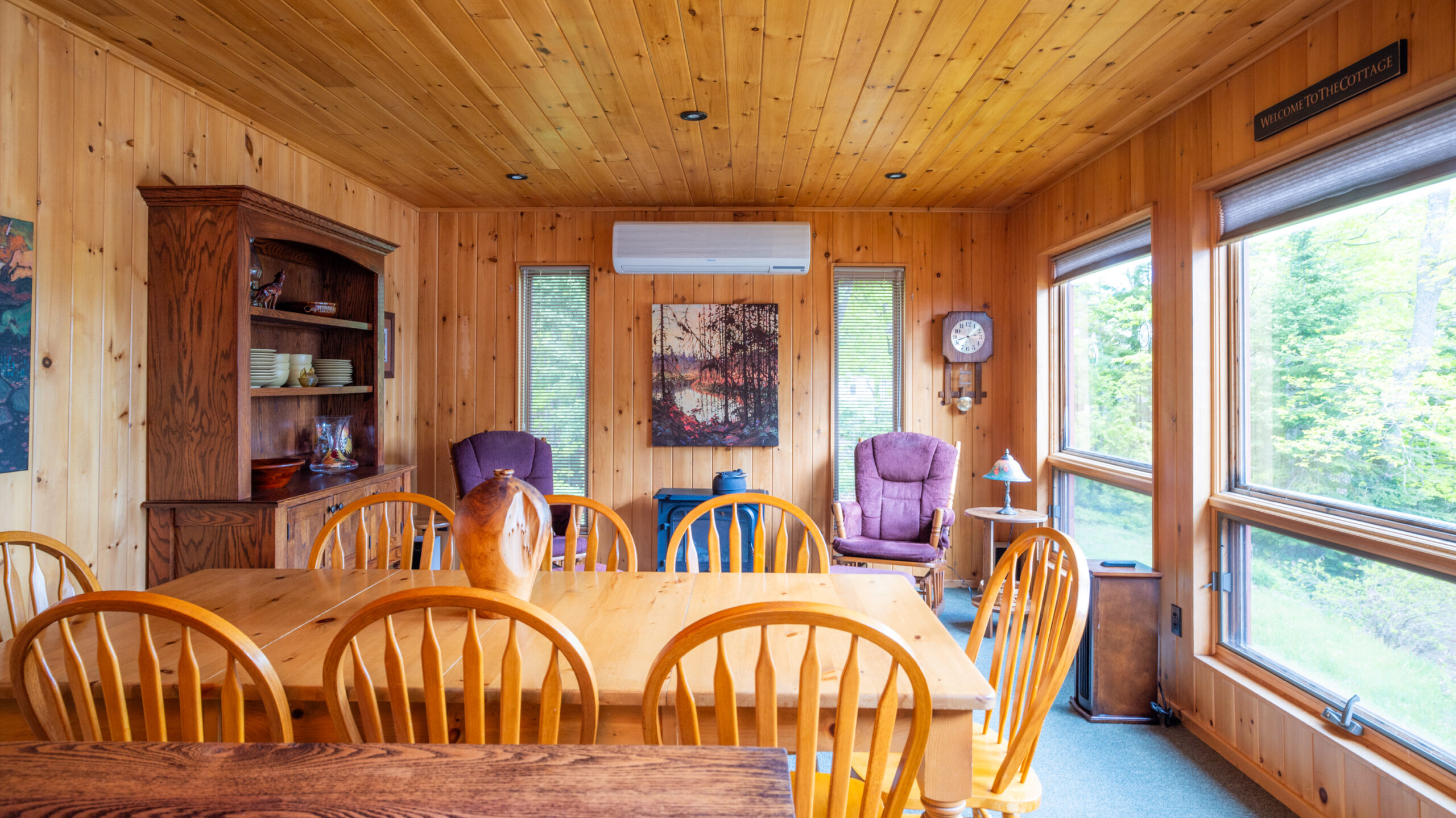 A light dining table with wood chairs in a wood-paneled room