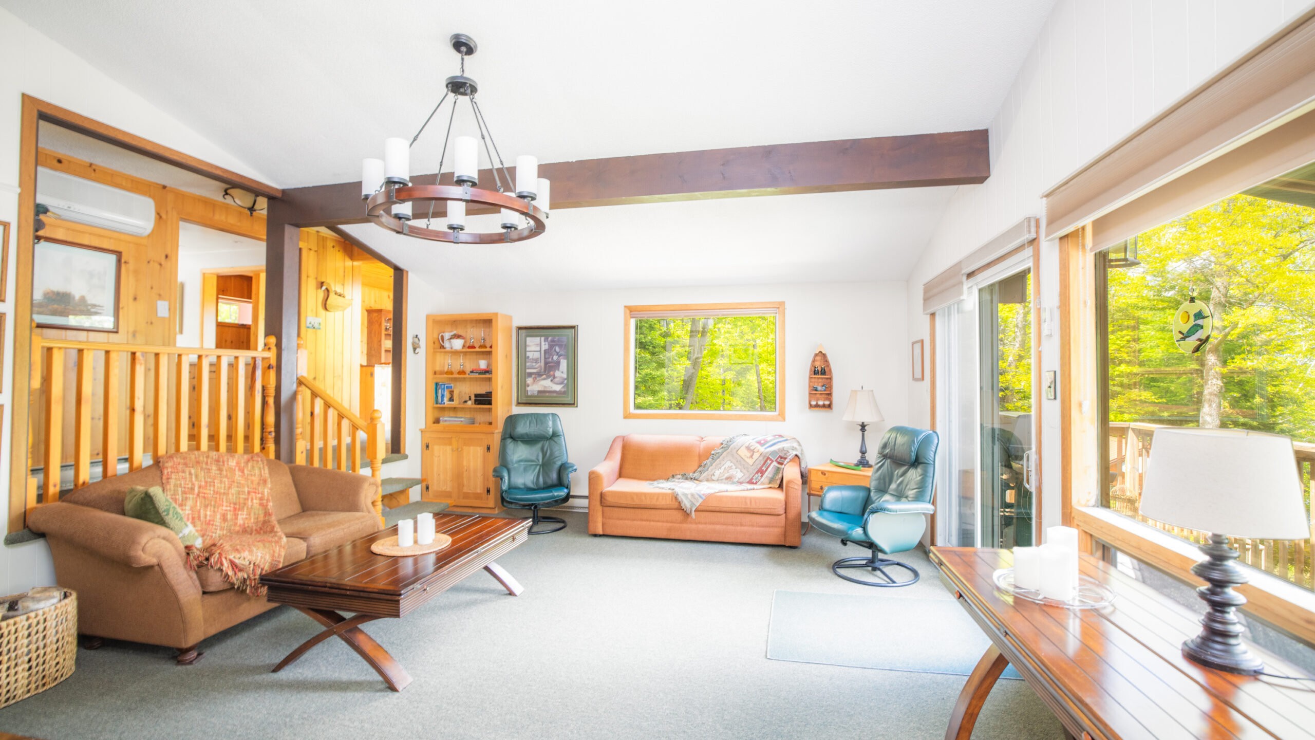An open-concept living area with green carpeting, a chandelier, and eclectic furniture