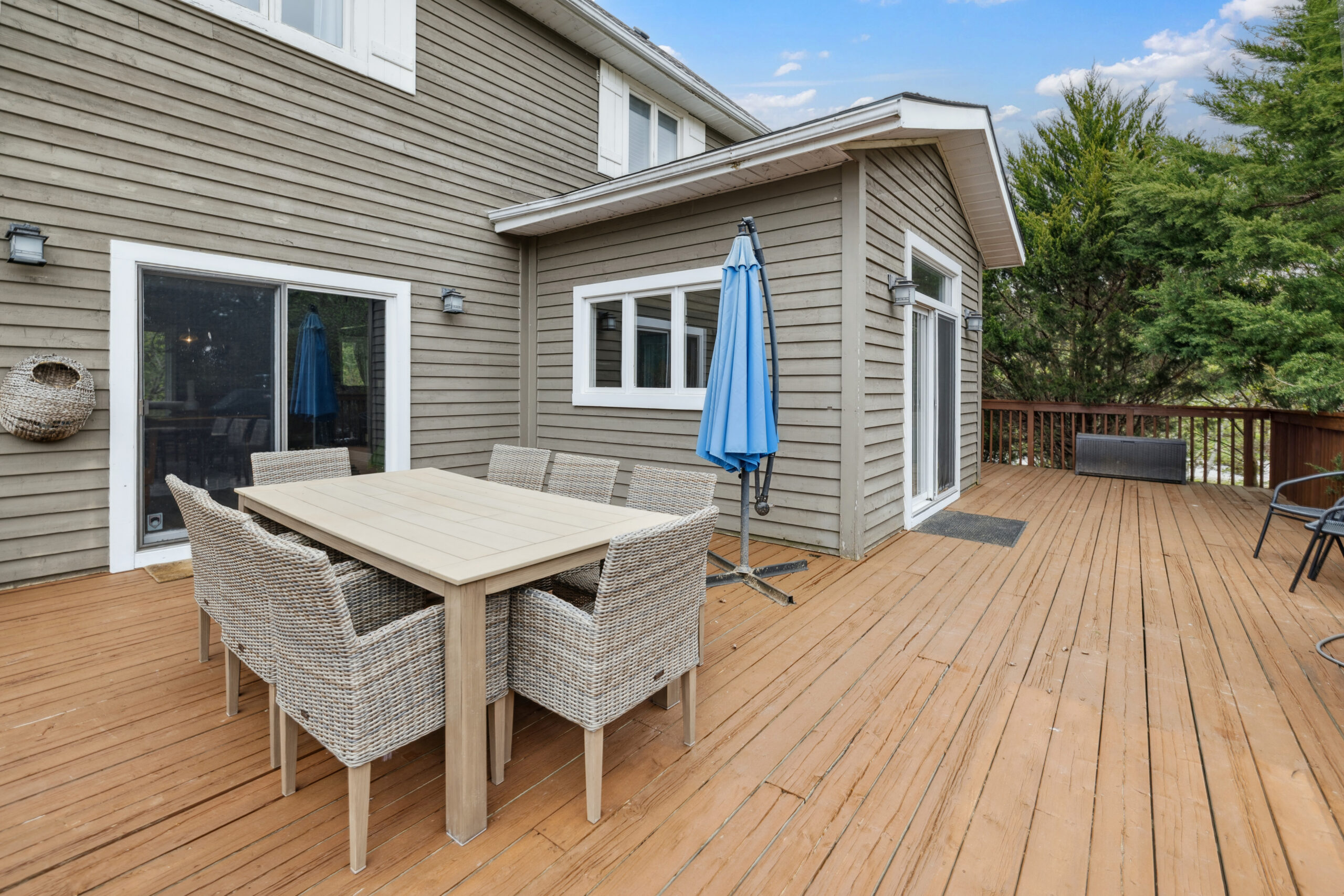 A brown deck attached to a brown-paneled cottage with an outdoor dining set