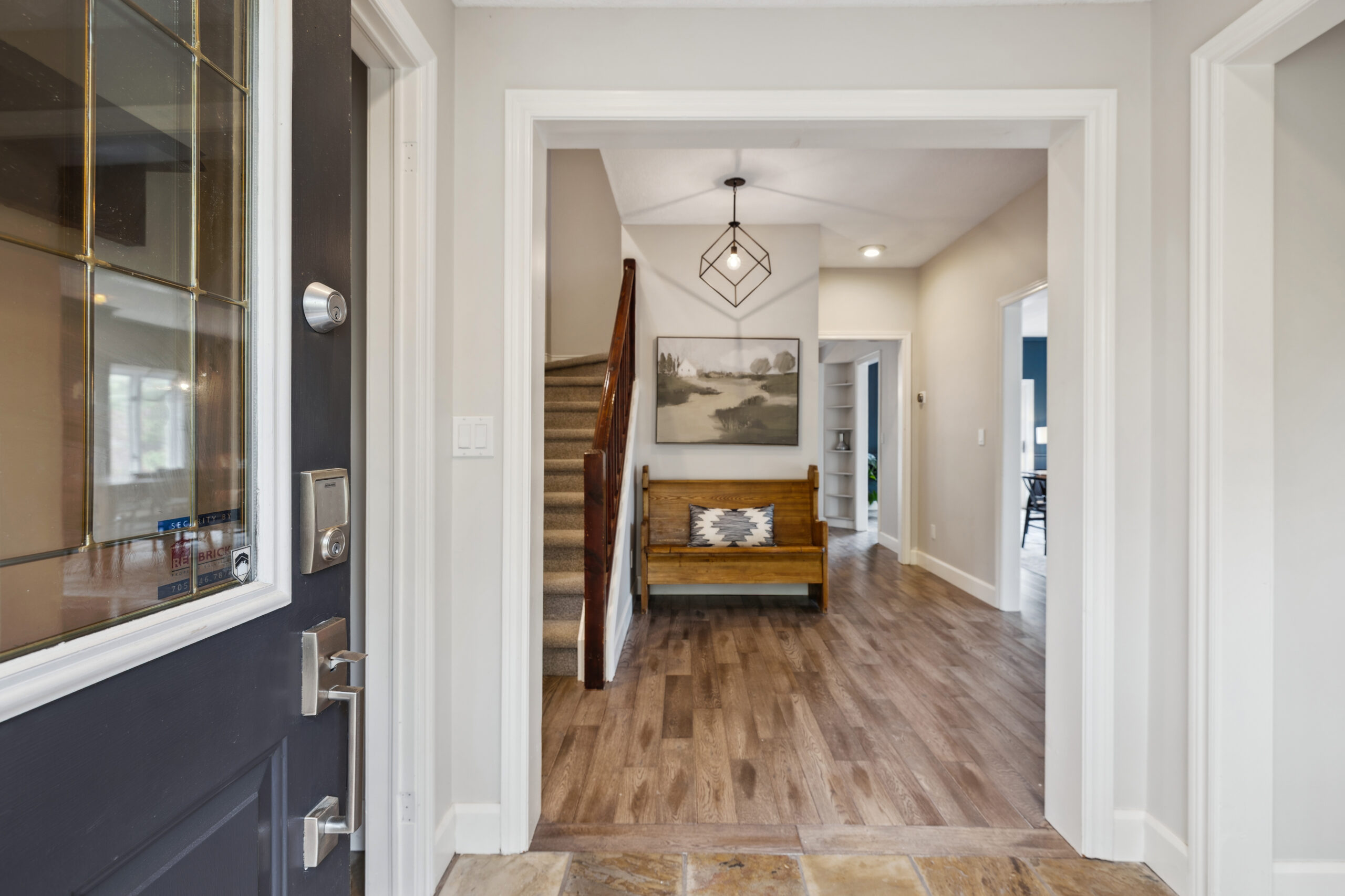 Blue front doors open to an open front entryway. Wood steps lead upstairs