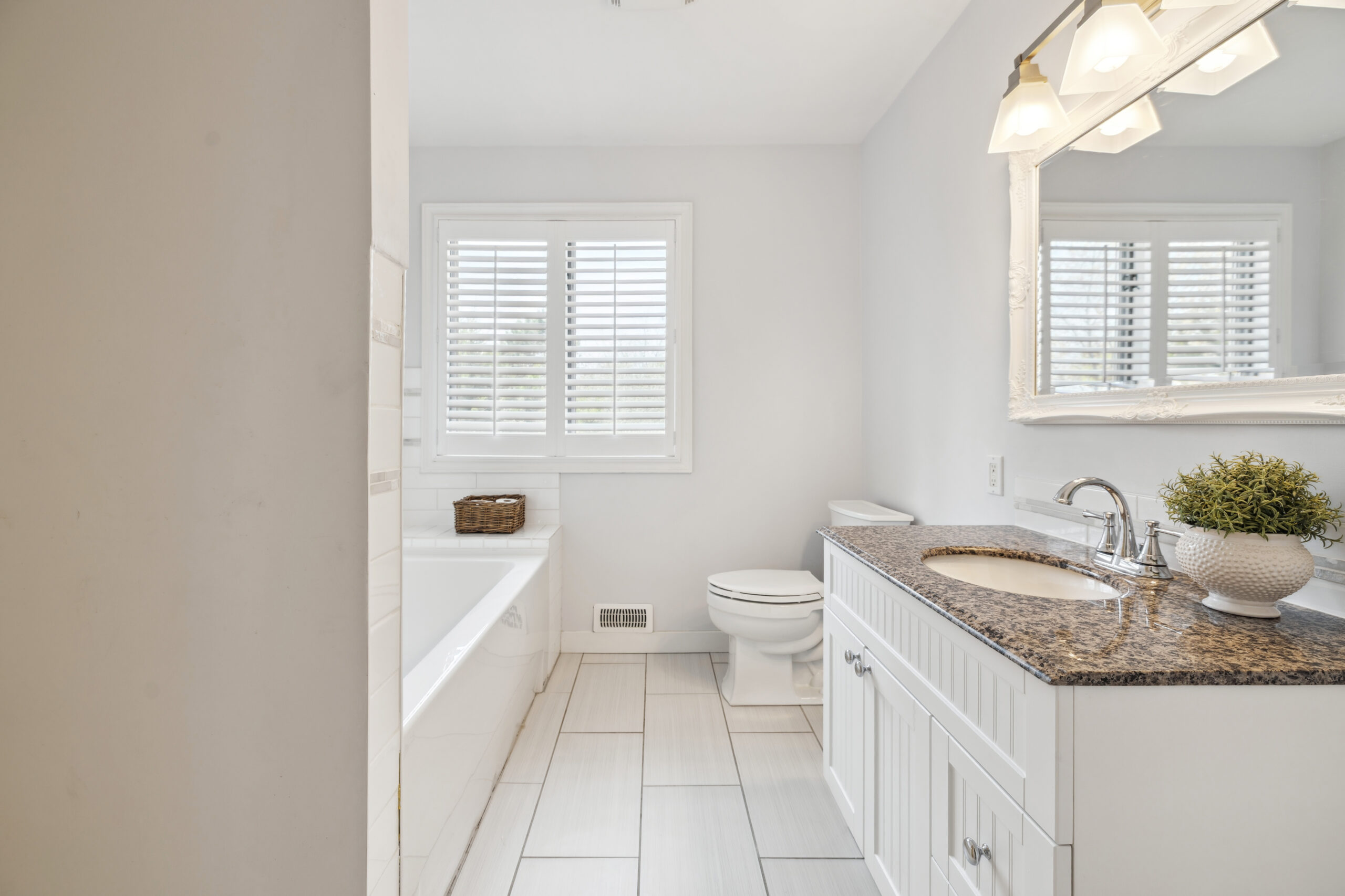 A bathtub faces a white vanity and toilet