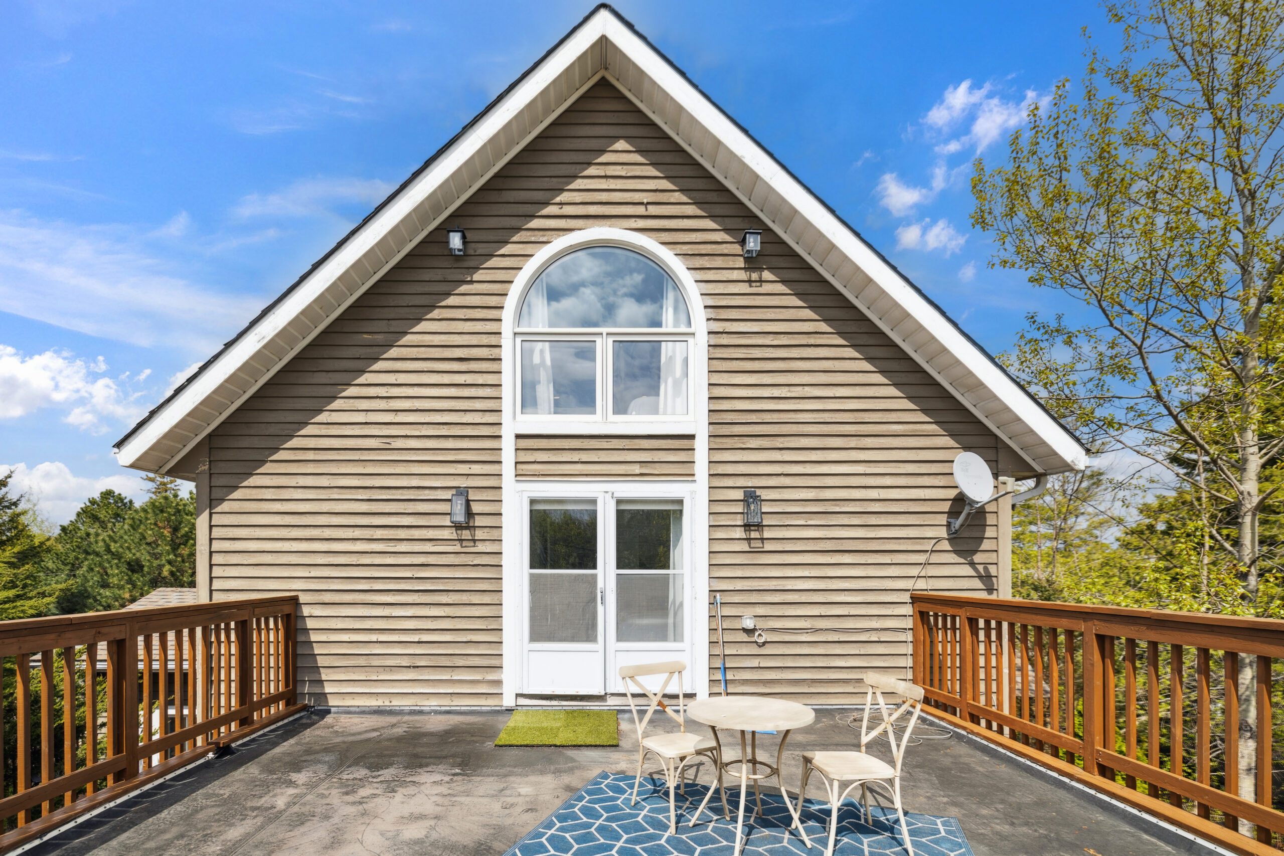 An A-frame upper-level cottage with a small patio set