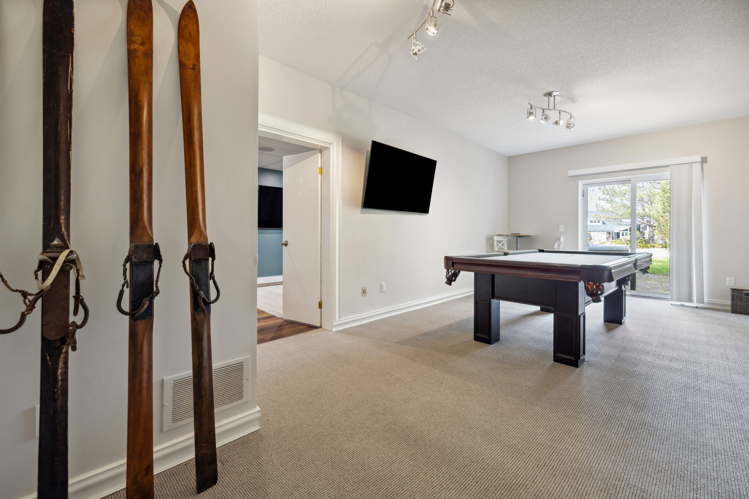 A pool table in a spacious room with a TV mounted on the wall