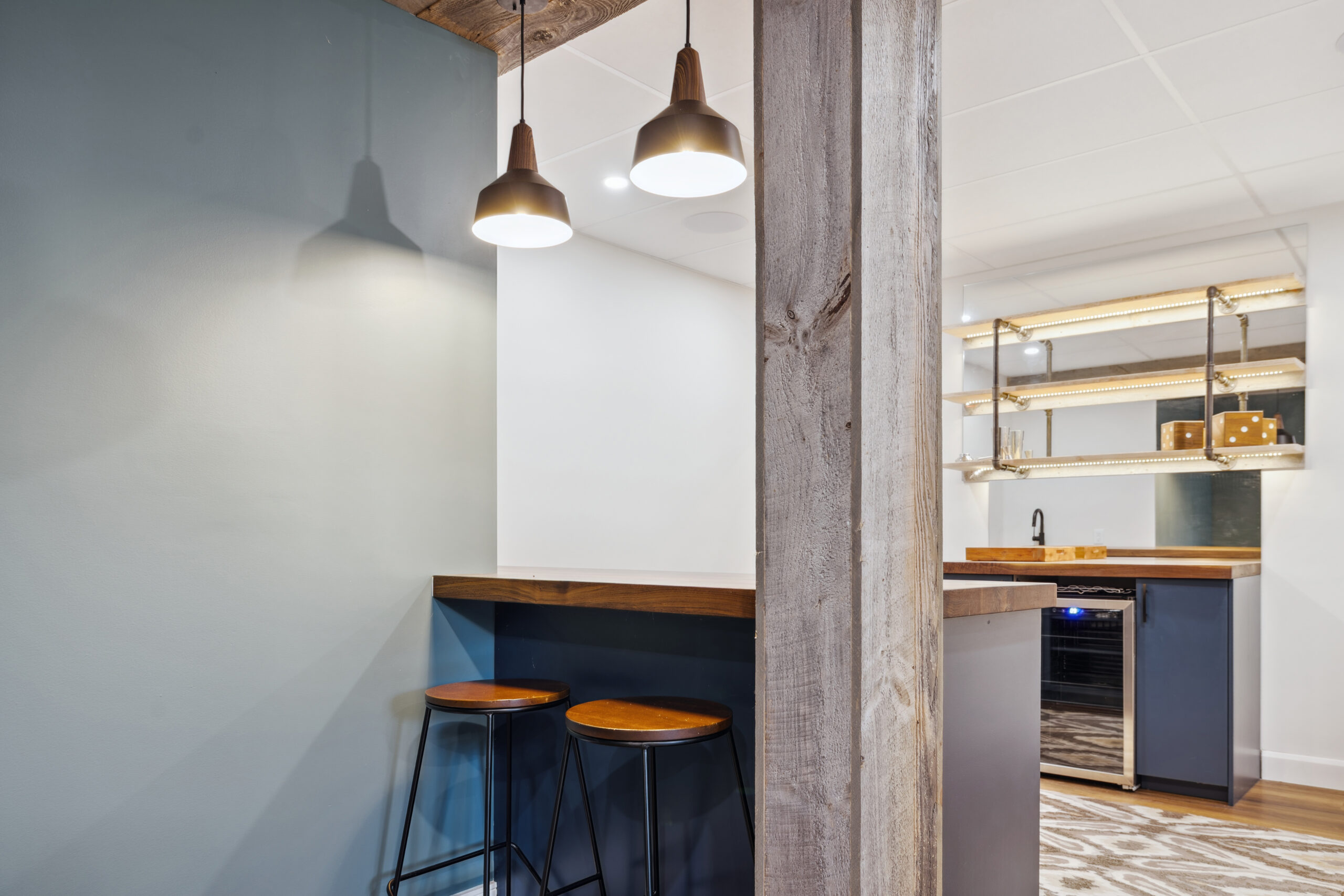 Two bar stools at a navy bar with a storage area behind