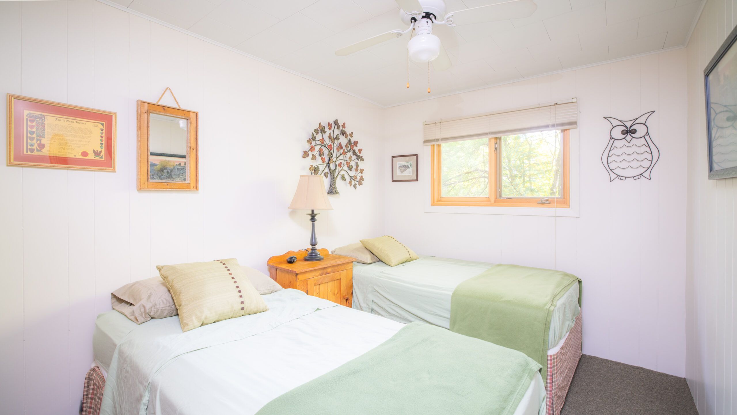 Two white beds with green covers in a white room