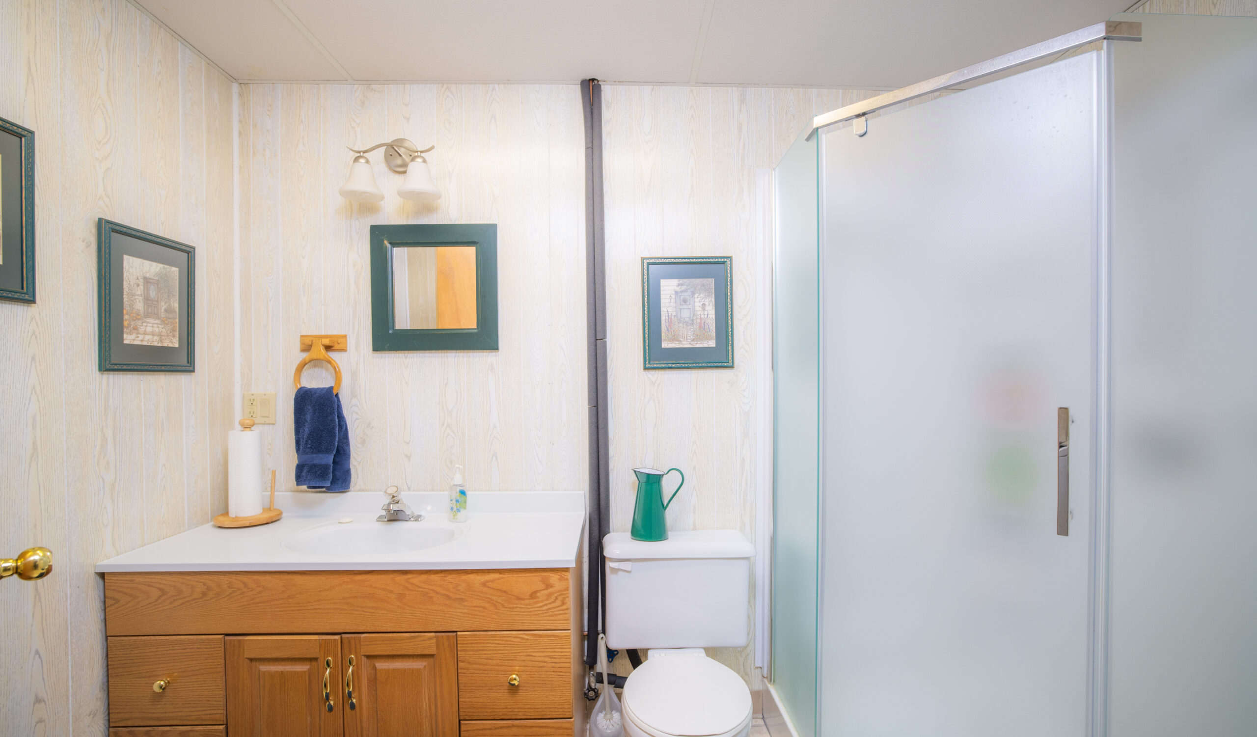 A white bathroom with a wood vanity and a glass walk-in shower