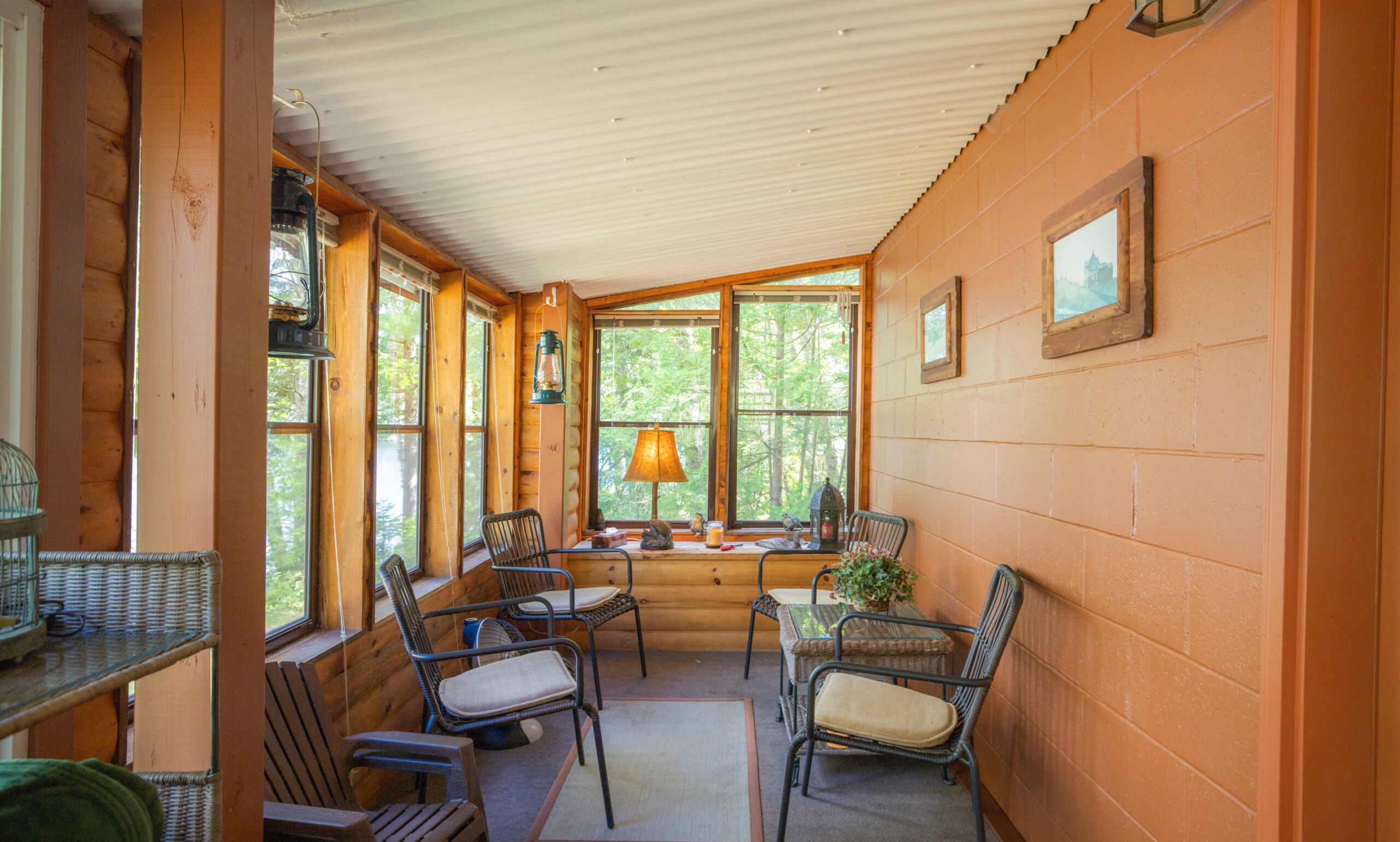 A wood paneled sunroom with screened windows