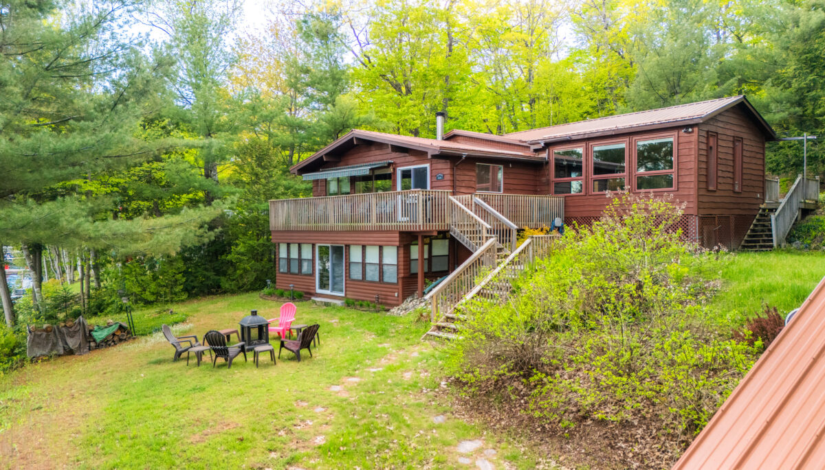 A two-level brown paneled cottage in the forest