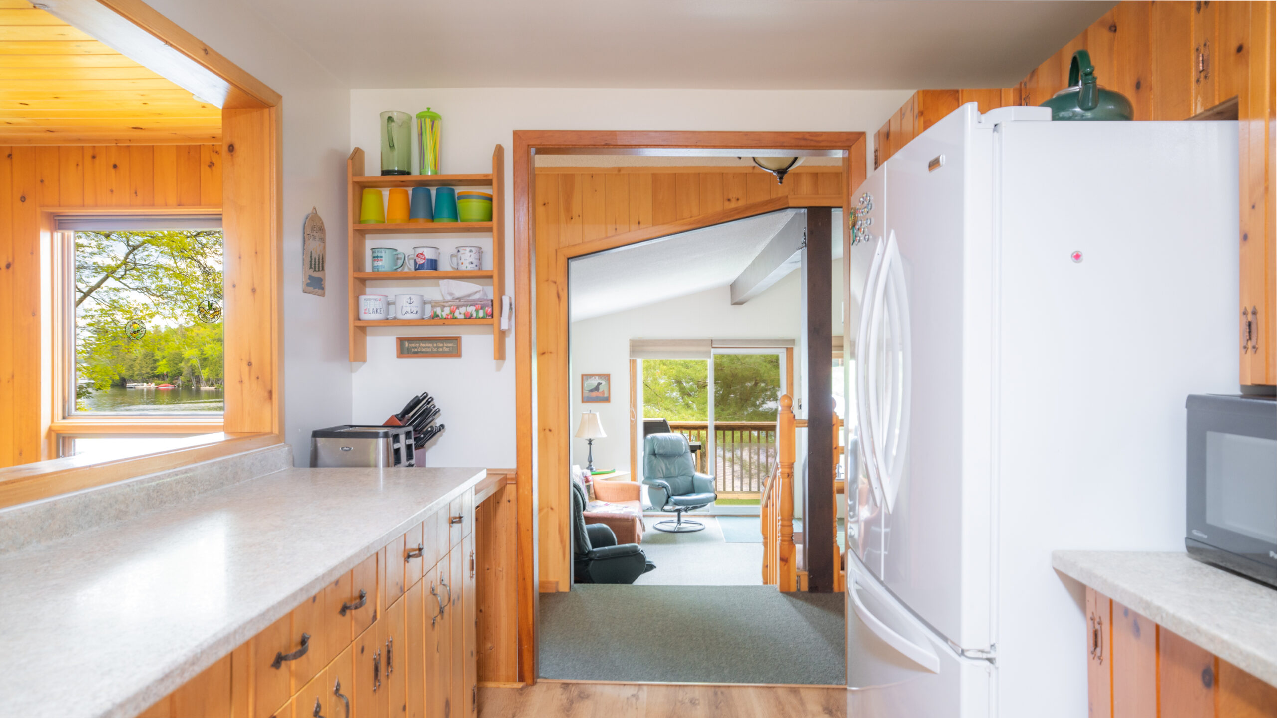A white and wood kitchen looks out into a carpeted living room