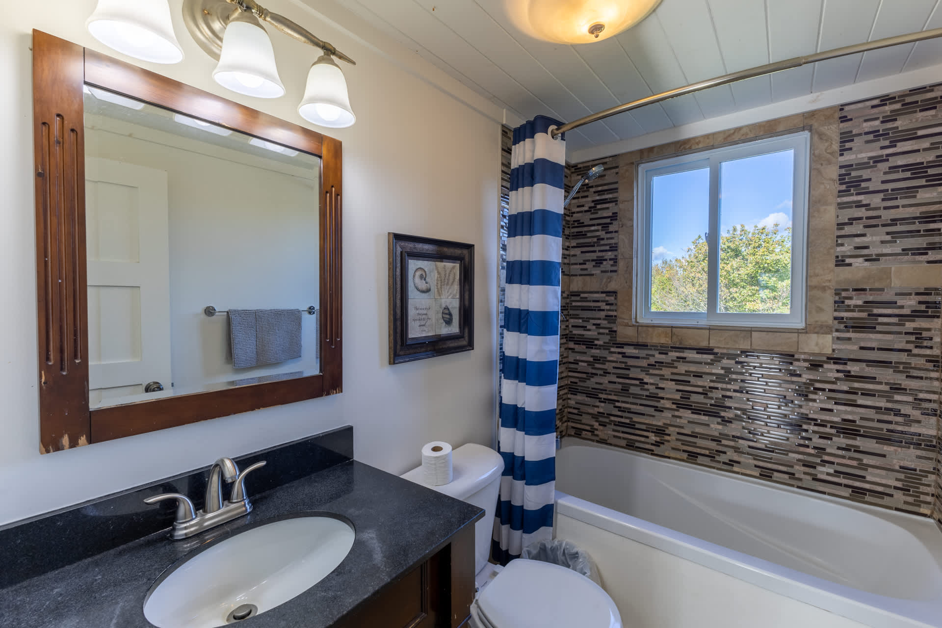 A dark brown vanity with a brown mirror above next to a tiled bathtub