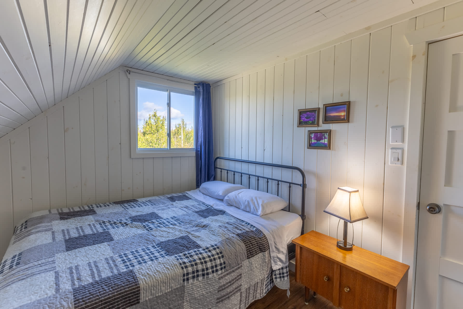 A bed with a blue and white quilt in a white bedroom