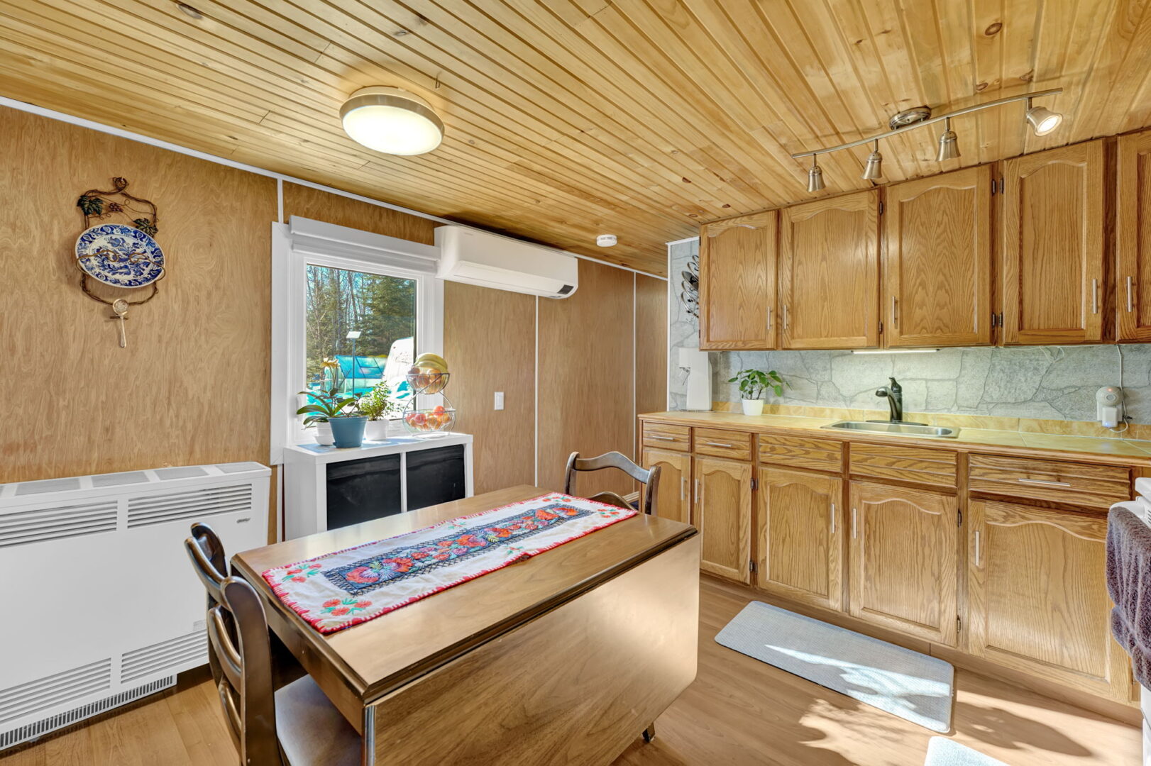 A wood-paneled kitchen with a wood table in the centre
