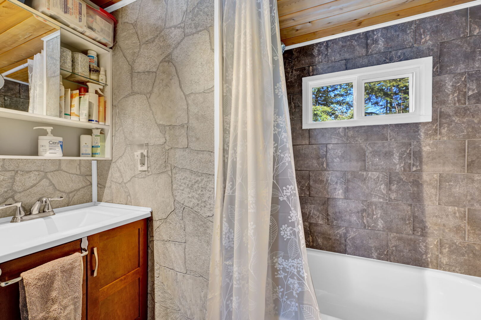 A bathroom with a grey stone shower and a translucent shower curtain