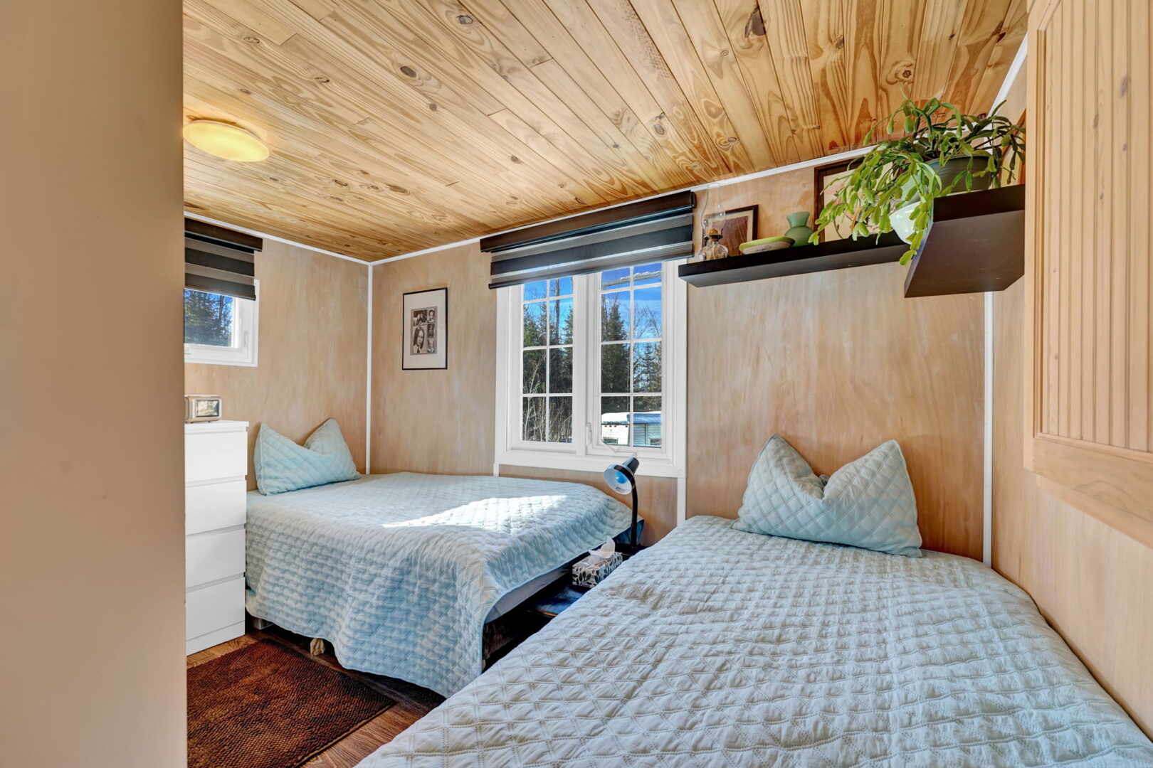 Two grey beds in an L-shape in a wood-paneled room