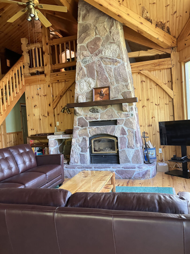 A tall stone fireplace in a cottage living room