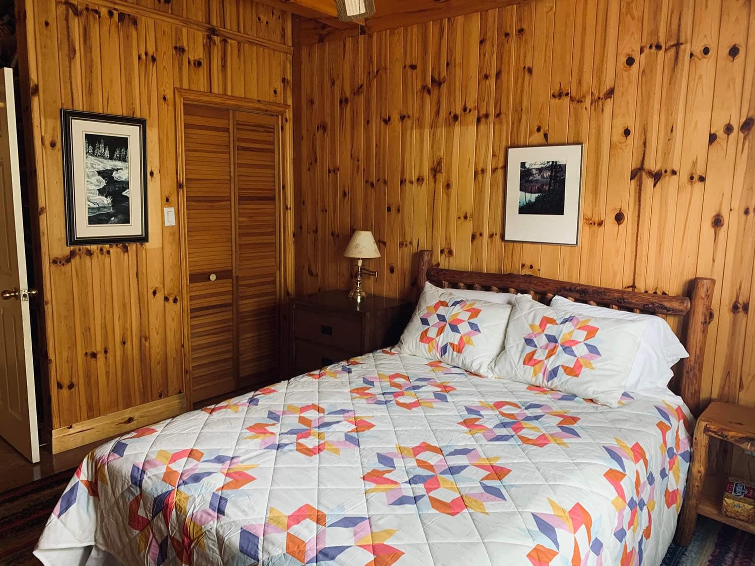 A white and pink bedspread on a bed in a wood room