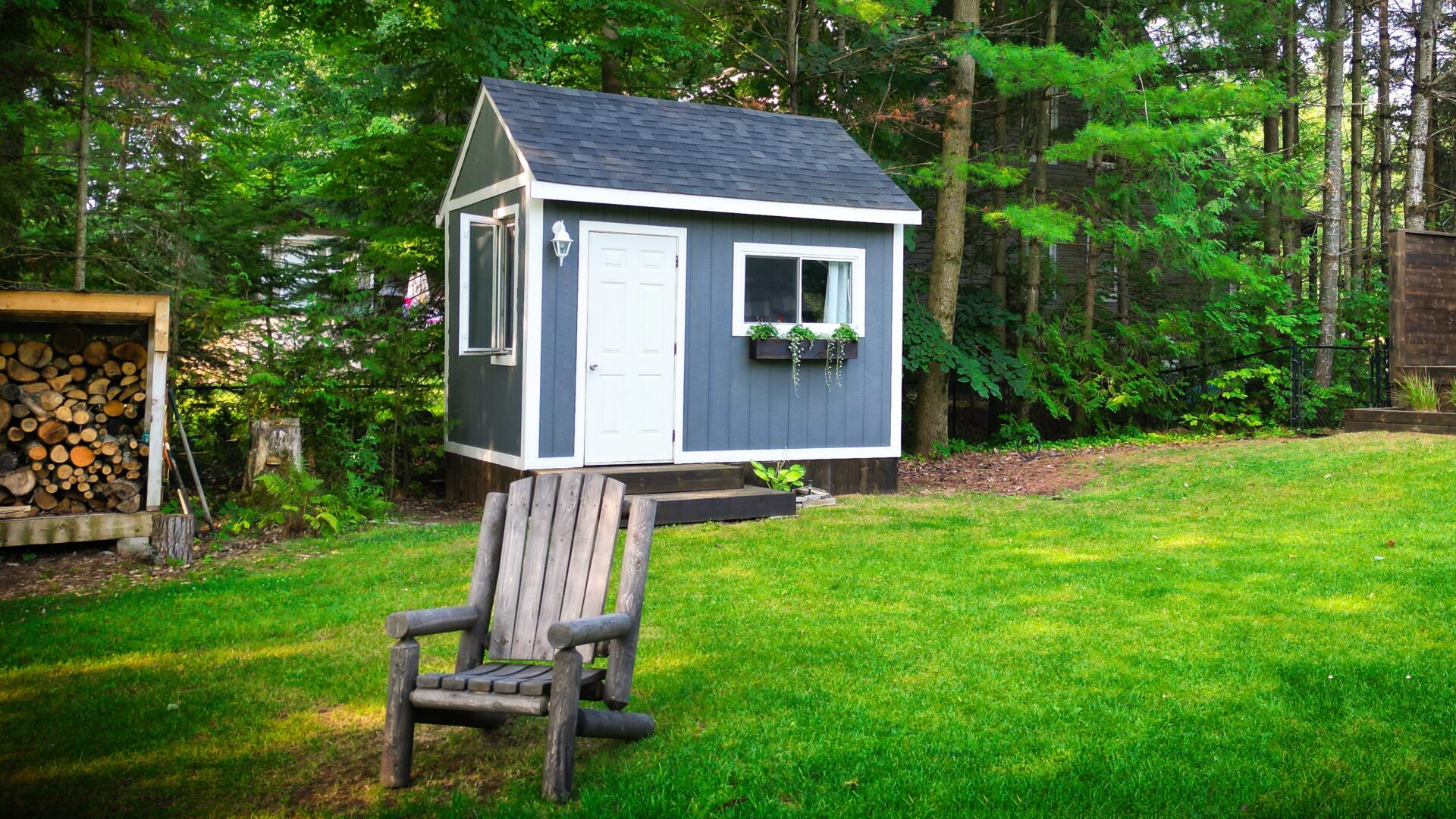 A blue-grey shed with a white door and white trim