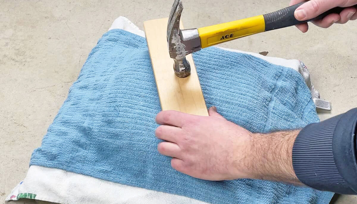 Someone using a hammer and pillow to flatten a pan