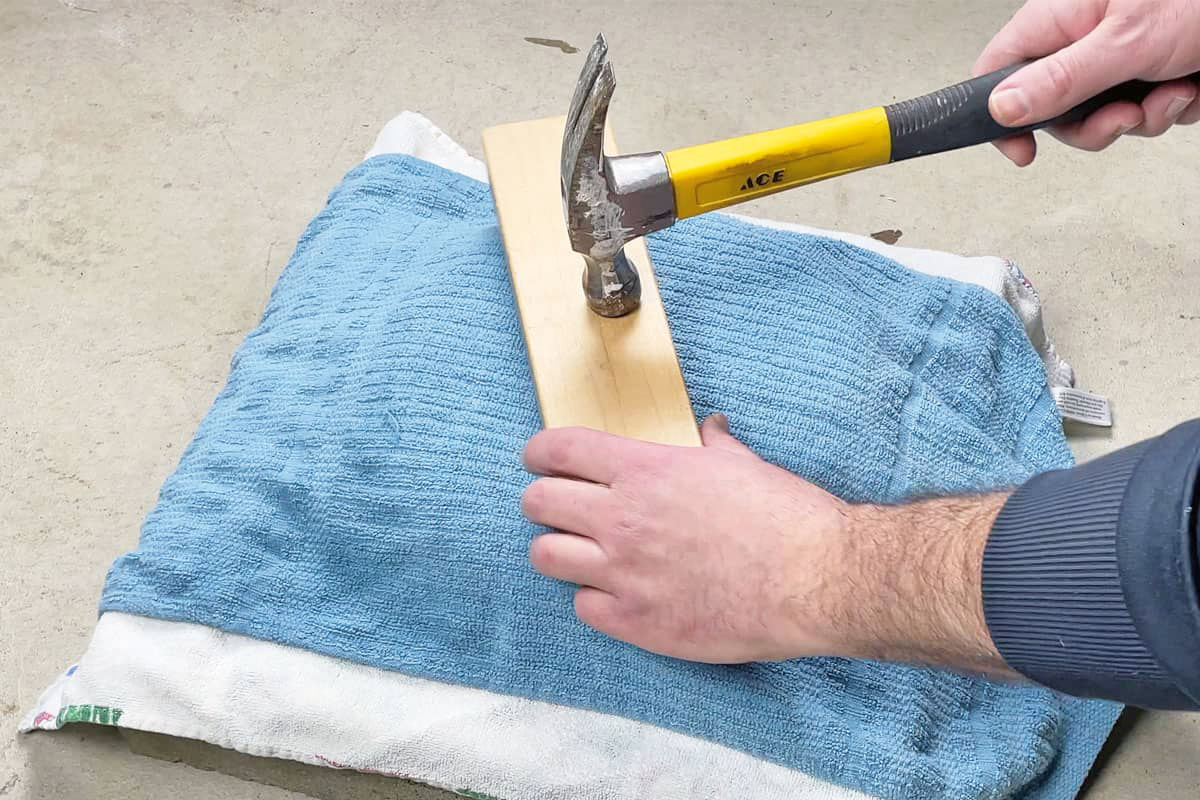 Someone using a hammer and pillow to flatten a pan