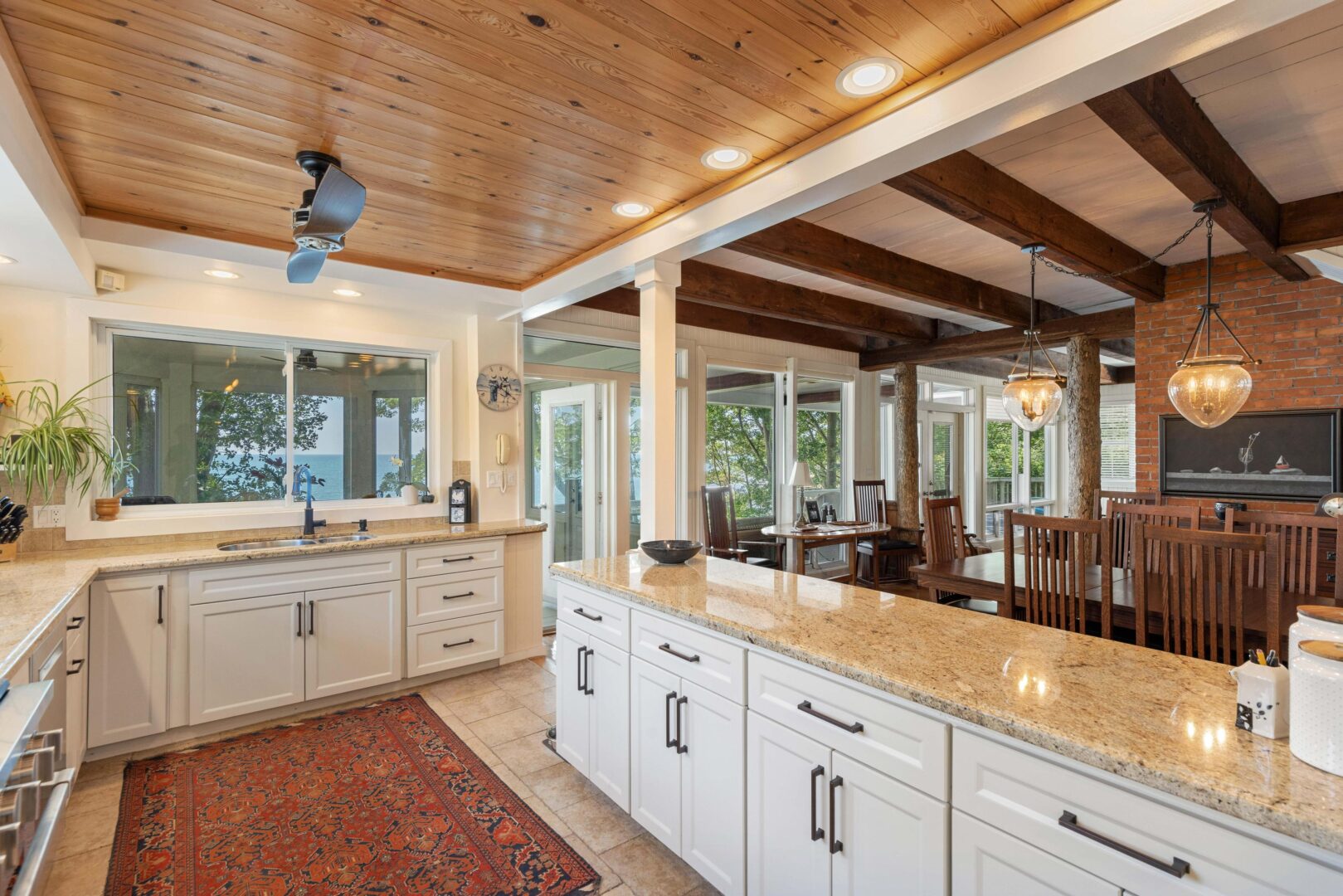 Spacious galley-style kitchen with granite countertops, white cabinetry, and wood-beamed ceiling