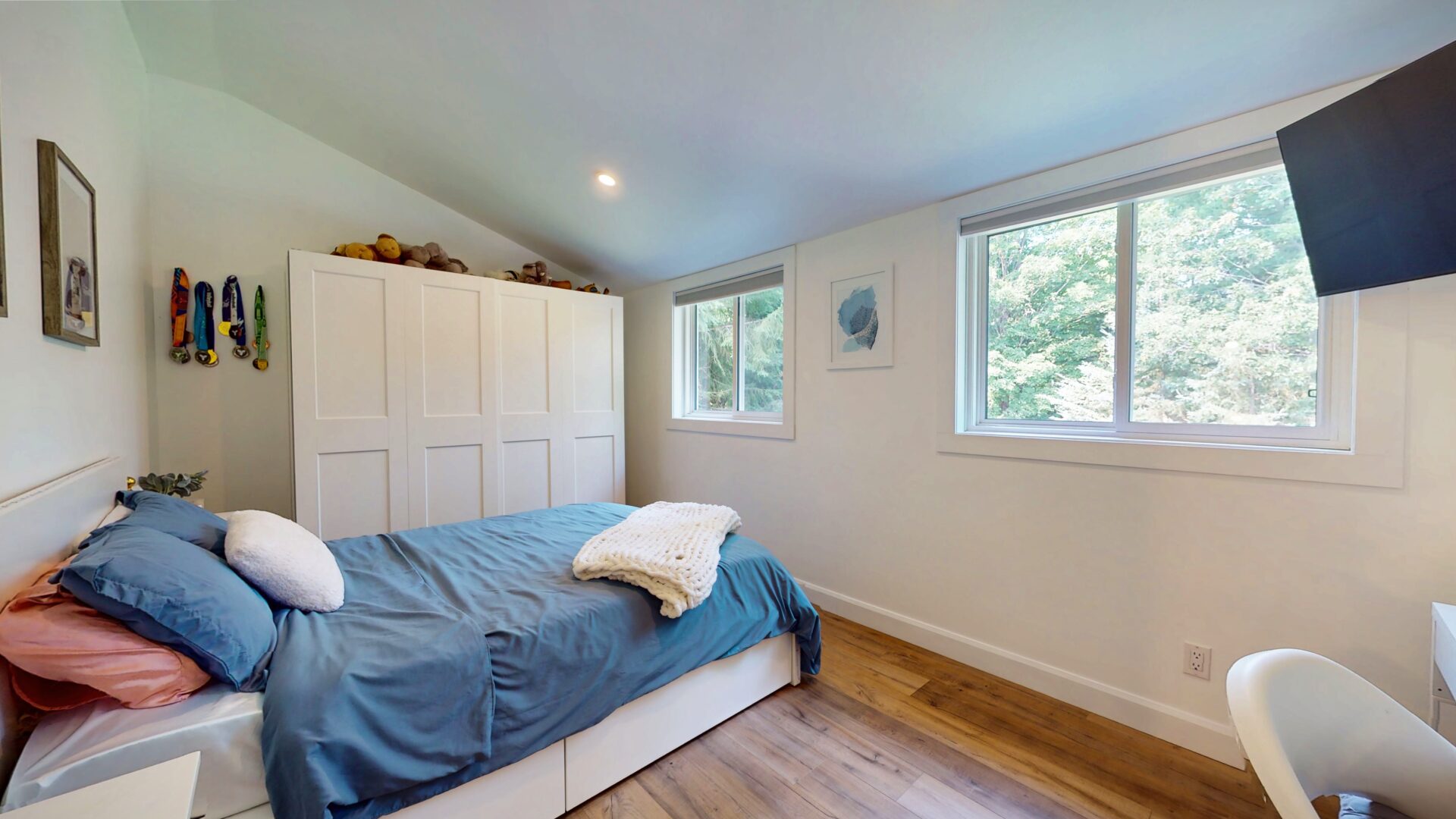 A blue bed next to a white closet in a white bedroom