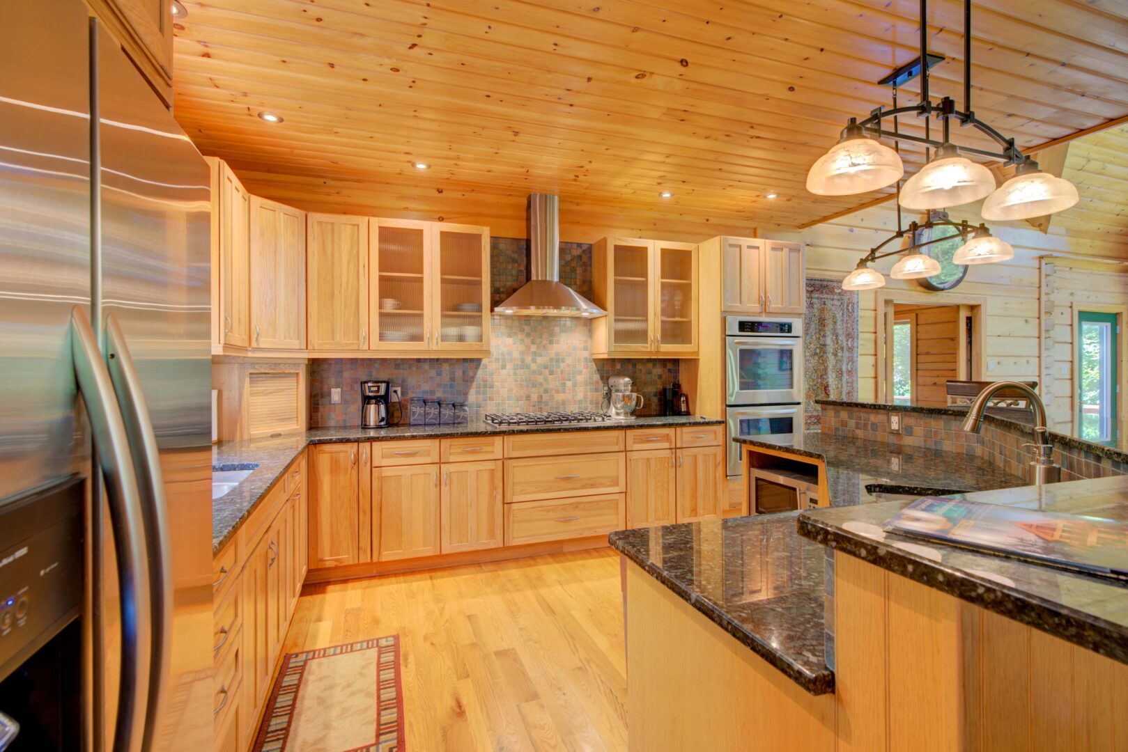 A wood paneled kitchen with dark countertops