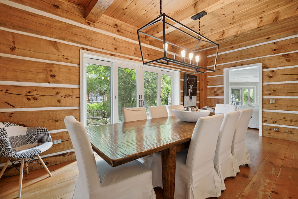 A rectangular wood table with covered white chairs in a wood paneled room