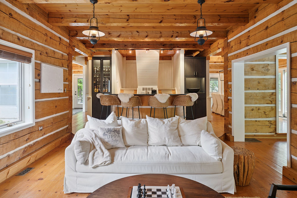 A white couch in front of the bar faces a round wood table