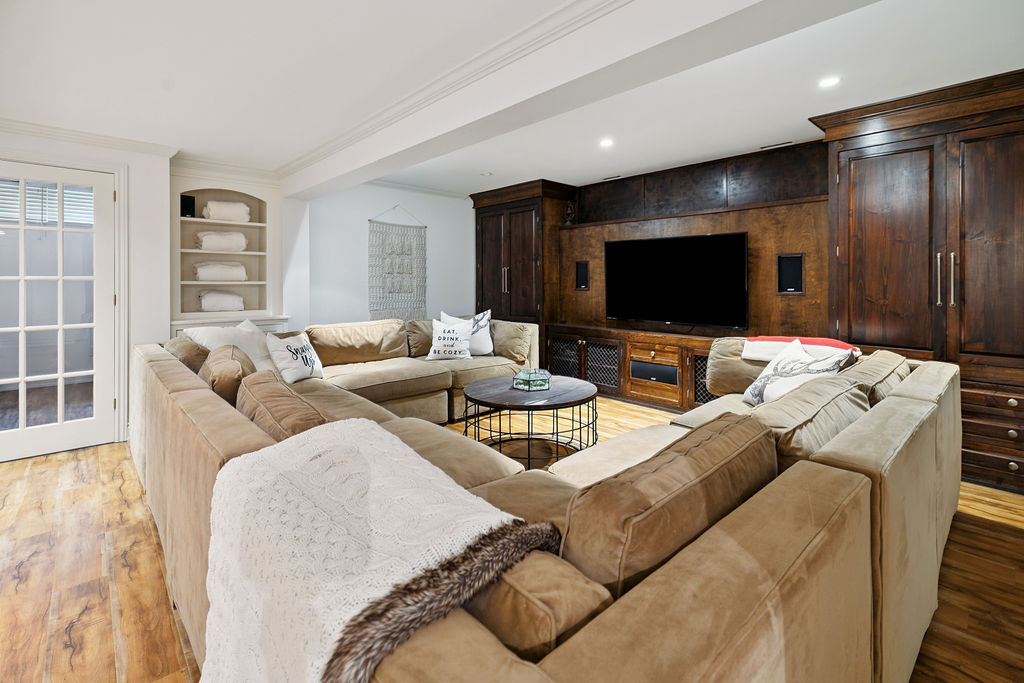 A brown suede couch faces a brown built-in TV area