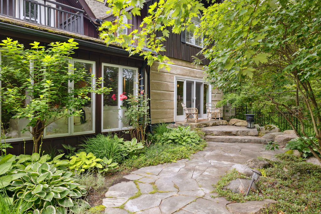 A dark paneled and stone cottage with a stone pathway