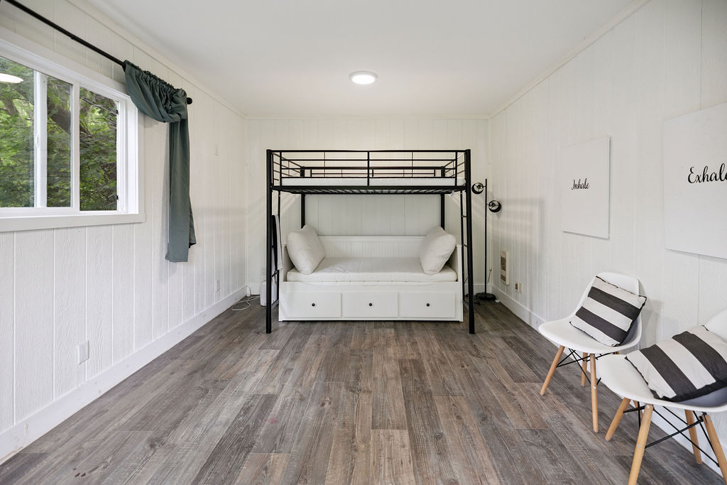 A loft bed in a white room with grey floors