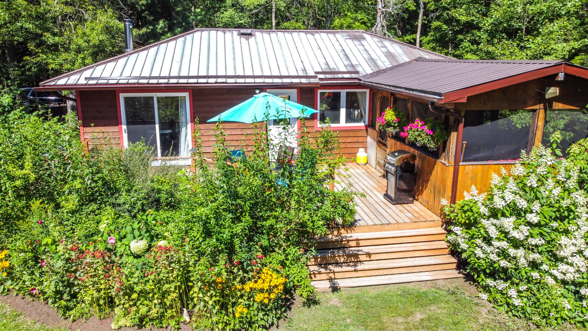 A wood cottage with a teal umbrella on the back deck