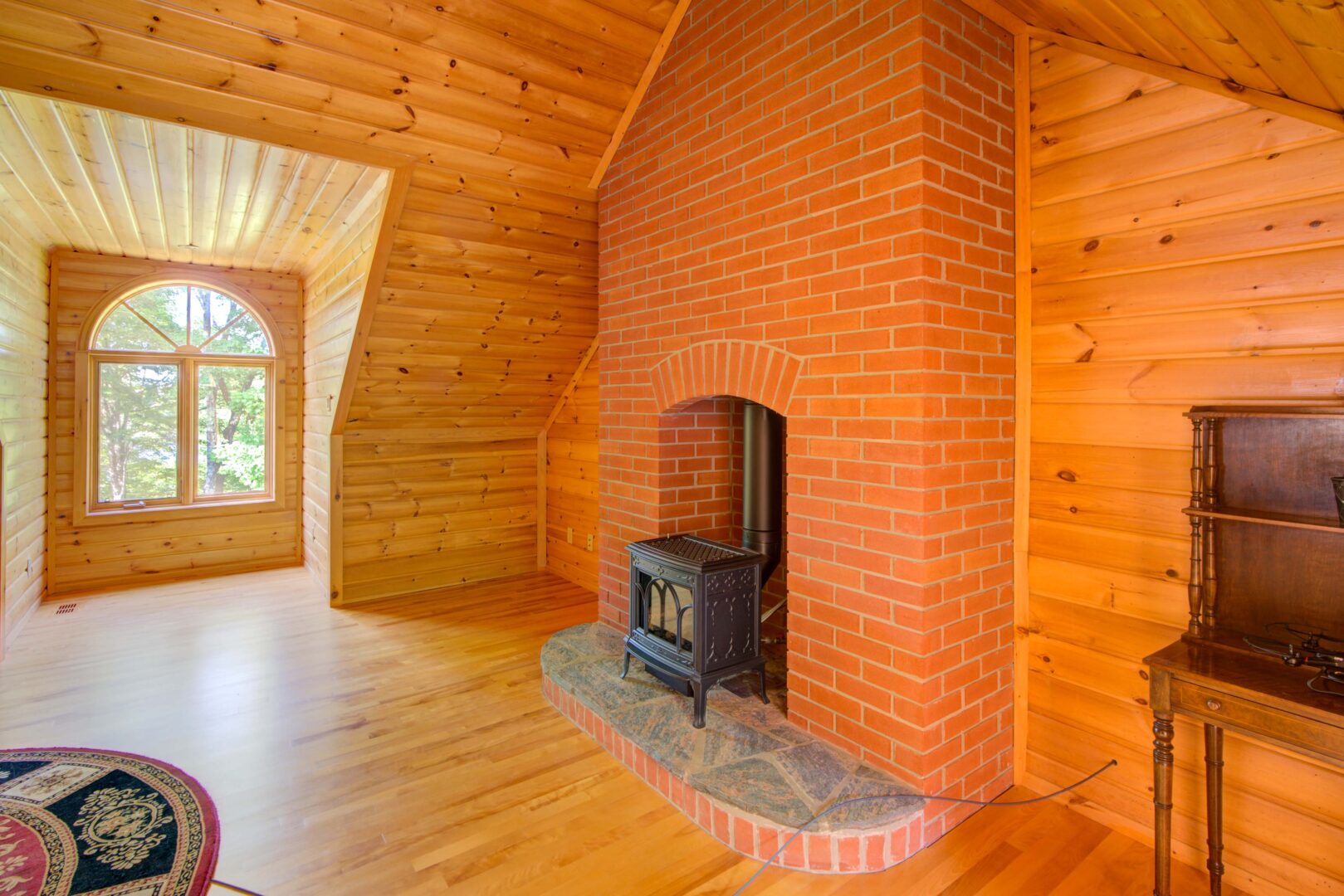 A wood paneled loft with a small woodstove