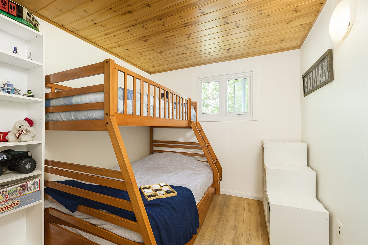 Wood bunk beds with white beds with a blue throw at the end