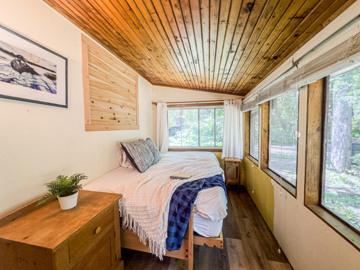 A white bed in a screened-in porch bedroom