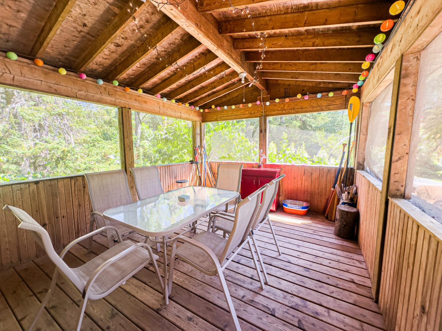 A wood screened-in porch with a white dining table and chairs
